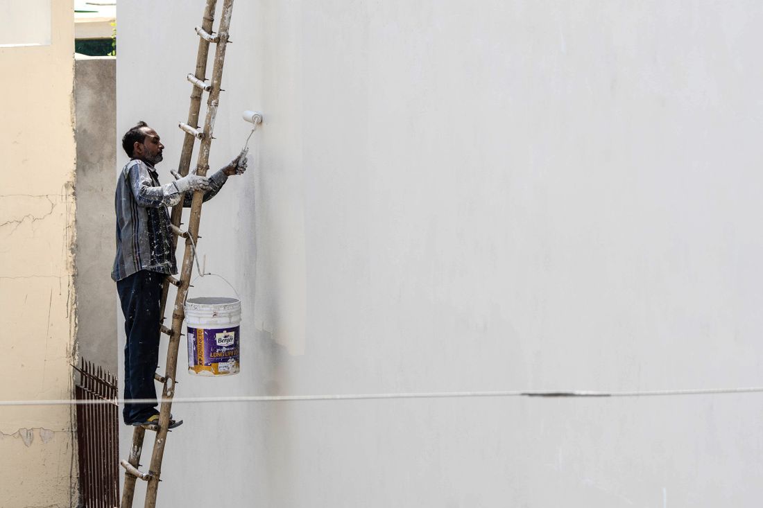 Painter on a ladder coating an exterior wall